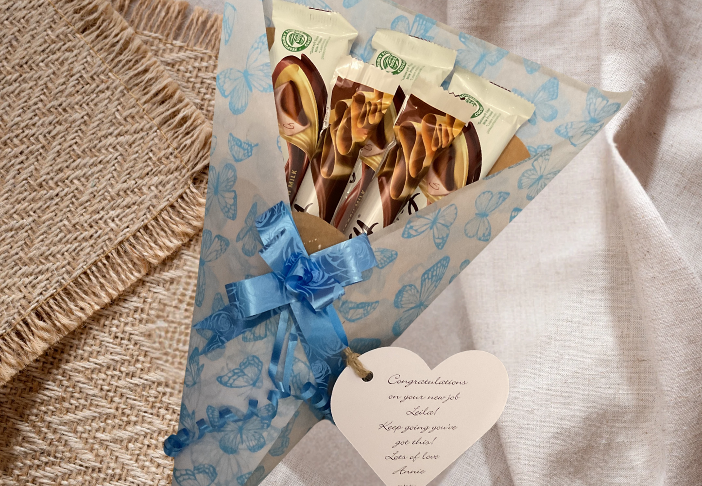 Galaxy chocolate bouquet wrapped in tissue paper with a gift tag and matching bow.