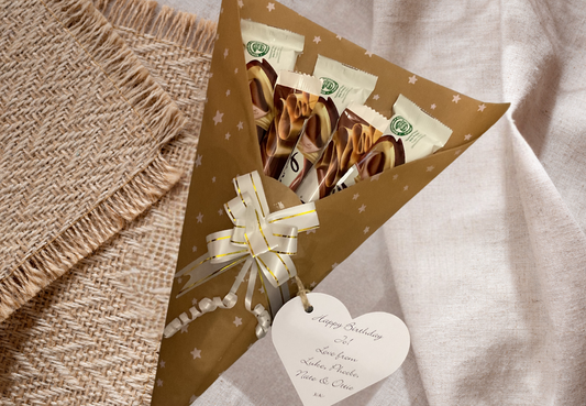 Galaxy chocolate bouquet wrapped in tissue paper with a gift tag and matching bow.
