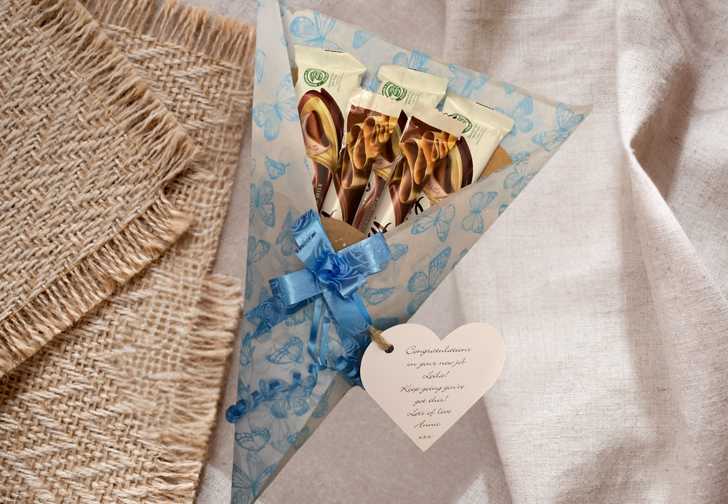 Galaxy chocolate bouquet wrapped in tissue paper with a gift tag and matching bow.